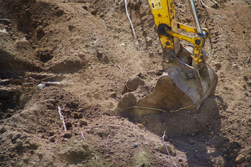 Excavator bucket digs into the ground, the beginning of construction work, the bucket of the excavator in the ground