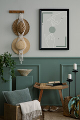 Warm and cozy composition of living room interior with mock up poster frame, braided bag, hat, wooden bench, stool, macrame, green stand and personal accessories. Home decor. Template.