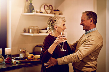Senior couple, wine and dance in the kitchen to celebrate anniversary date, dinner or lunch at...