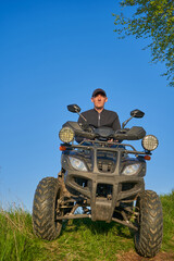 active recreation on a quad bike, a man sits on a quad bike and looks at the sunset