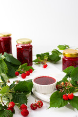 Homemade summer preservation, raspberries jam in jars, jars with jam and raspberry sprigs