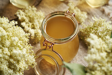 Elderberry flower syrup in a glass jar with fresh blossoms