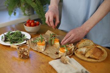 cooking Italian dish. bruschetta. in the photo, hands are preparing a dish of bread, herbs, jamon, cheese and honey. home-cooked lunch and dinner