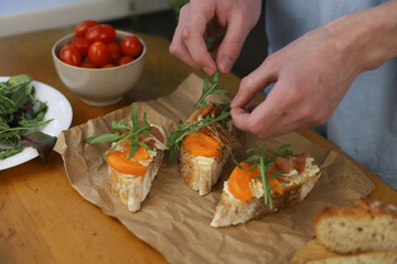 cooking Italian dish. bruschetta. in the photo, hands are preparing a dish of bread, herbs, jamon, cheese and honey. home-cooked lunch and dinner