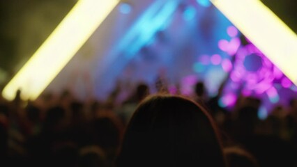 Silhouette hands of audience crowd people enjoying the concert. People with raised arms on music live event. People jumping and dancing at party concert with lightshow. 4K, UHD