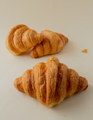 freshly baked croissants in a colored background, green, black, or neutral. with fresh flowers newspaper, cappuccino showing layers and crumbles and filling with berries