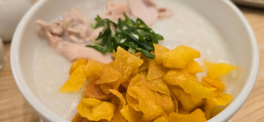 rice porridge with shredded chicken called bubur ayam served with crackers and sliced spring onion and others condiments