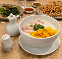 rice porridge with shredded chicken called bubur ayam served with crackers and sliced spring onion and others condiments