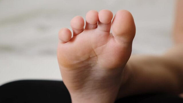 The foot of child close-up. Small tender healthy sole of kid. Beautiful toes. White soft skin. Part of the body. Childhood background. Slow motion. High quality 4K