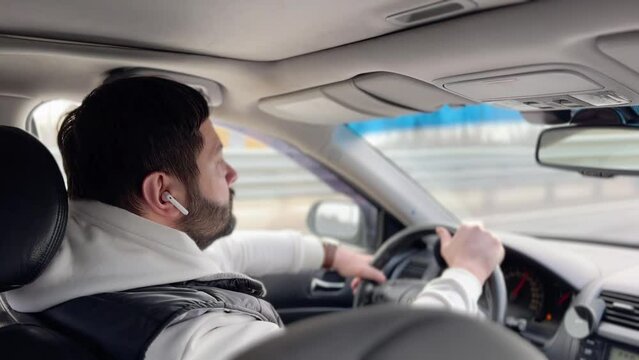 man driving car on highway and listening to music with earpods