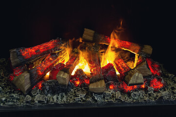 The logs of the fireplace burn with a bright fire. Artificial decorative fireplace with imitation of fire.