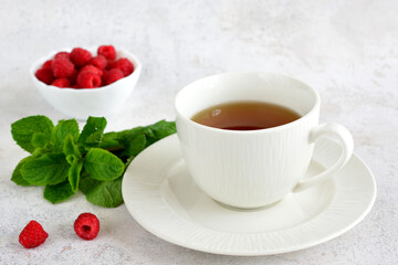 a cup of mint tea and a plate of raspberry close up