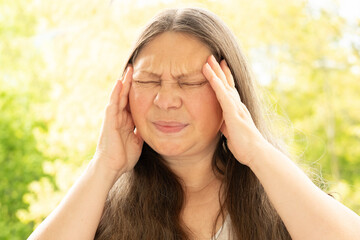 diseased mature woman experiences severe headache, holding head, Hot flashes during menopause,...