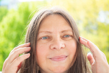 Caucasian positive 50-year-old attractive woman with long hair poses gracefully, pretty face close...