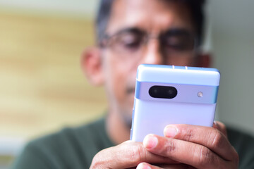 South Asian man with a mobile phone in hand. Digital life concept, shallow depth of field.