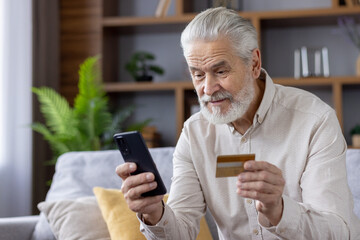 Senior man using smartphone and credit card for online shopping at home