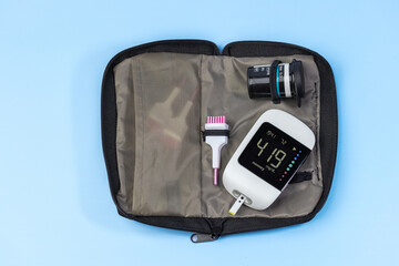 A blood glucose meter with a screen that reads 419 sits in a black case. The case is open and the...