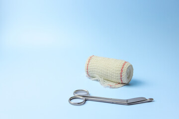 A pair of scissors and a roll of gauze are on a blue background. Concept of preparedness and care...