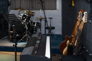 Electric piano in the recording studio against the background of blurred guitars, drum kit,...