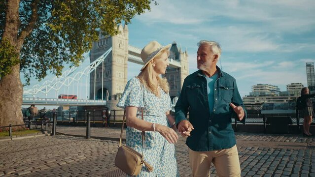 Happy senior couple spending time together in London city. Beautiful woman and man walking and having fun near the thames river. Concepts about seniority, lifestyle and travel
