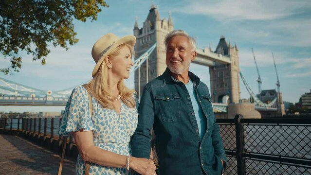 Happy senior couple spending time together in London city. Beautiful woman and man walking and having fun near the thames river. Concepts about seniority, lifestyle and travel
