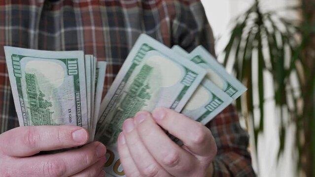 A man proudly holds a stack of cash in his hands, symbolizing prosperity and financial success.