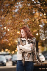 A lively redhead grins with delight, spreading warmth on the autumn streets.
