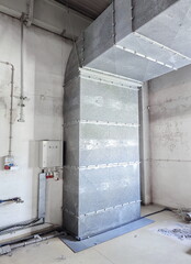 Large, metal, industrial size air ventilation duct inside factory floor. Wide angle, no people