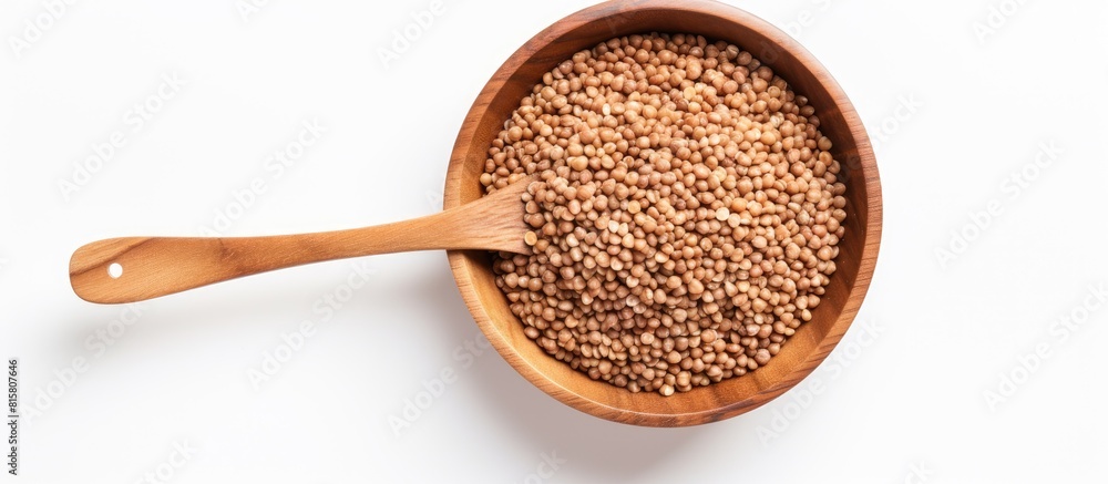 Poster a top view image of buckwheat kernels in a wooden bowl with a spoon set against a white background t