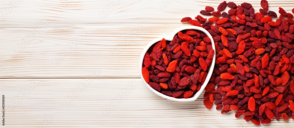 Poster top view of a heart shaped arrangement consisting of dried goji berries placed on a white wooden tab