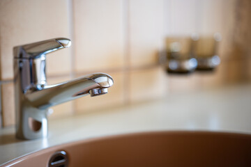 Silver, stainless steel bathroom water faucet. Close up shot, shallow depth of field, no people