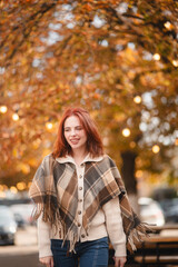 A delightful redhead smiles brightly, adding a touch of happiness to the autumn streets.