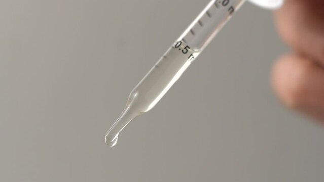 Macro video of dropper with transparent liquid.