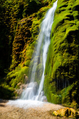 “Dreimühlen Wasserfall“ (three mills cascade) at Ahbach creek in Nohn (Eifel, Germany). The tall cascade is a popular sight and natural reserve in scenic valley with bright green moss on limestone.