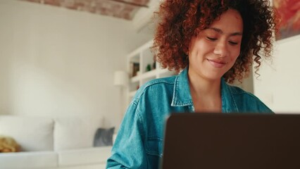 Young happy woman working on laptop indoors at home