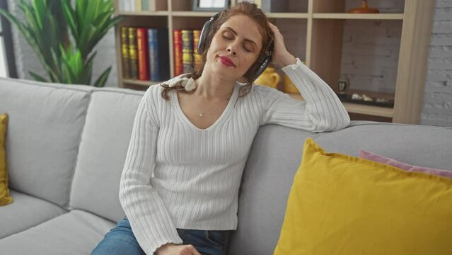 A serene young woman enjoys music with headphones in a cozy indoor setting