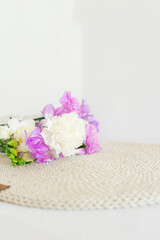 Beige wicker table napkin and purple and white carnation flowers close up. Handmade round tablecloth. Organic tableware