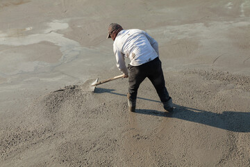 Construction worker uses trowel to level cement mortar screed. Concrete works on construction site....