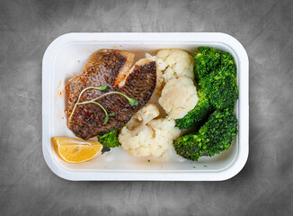 Sea bass fillet, blanched broccoli and cauliflower. Healthly food. Takeaway food. Top view, on a...