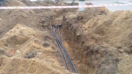 A trench was dug next to trees and the asphalt road to replace cables, pipes and other utilities....