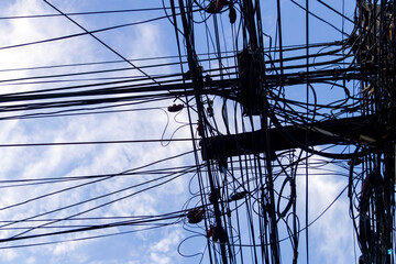A tangled mess of electrical wires against a blue sky.