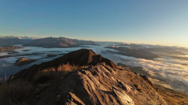 View of sunrise shining over summit of Roys Peak and foggy mountain over Lake Wanaka in autumn at New Zealand