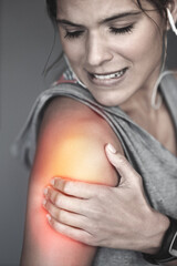 Woman, shoulder injury and pain for sport in studio with red glow, medical trauma and muscle...