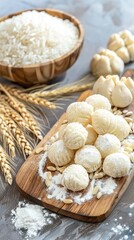 Fototapeta premium rice flour, rice dumplings, and a solitary ear of wheat arranged artfully on a wooden board, with white grain powder in a small bowl beside round white buns.