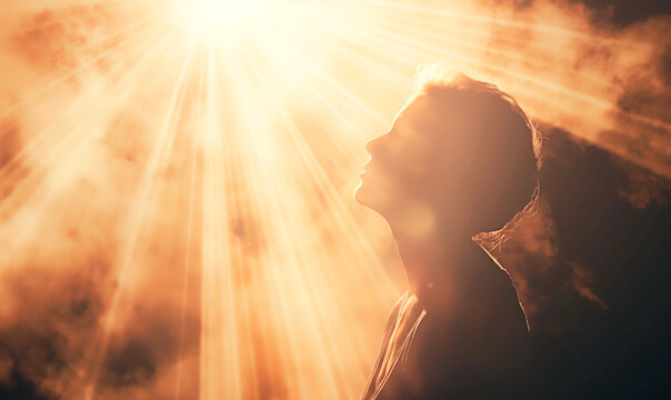 A person in sacred communion with God. Concept of ethereal connection with rays of divine light on praying person.