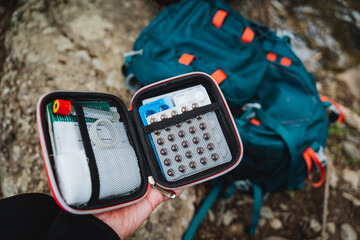 Individual displaying a first aid kit next to a backpack