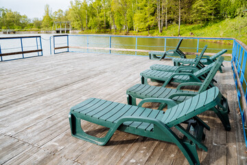 Outdoor leisure area with green lounge chairs on a hardwood deck by the lake