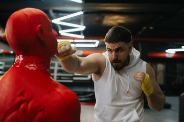A man trains with a boxing dummy in the gym.