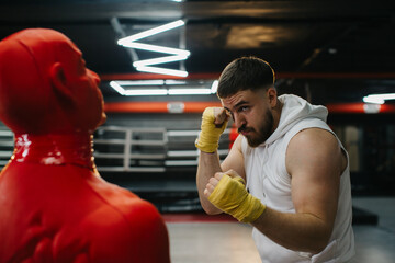 A man trains with a boxing dummy in the gym.