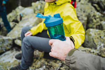 Bluecollar worker in yellow jacket sits on rock with blue water bottle